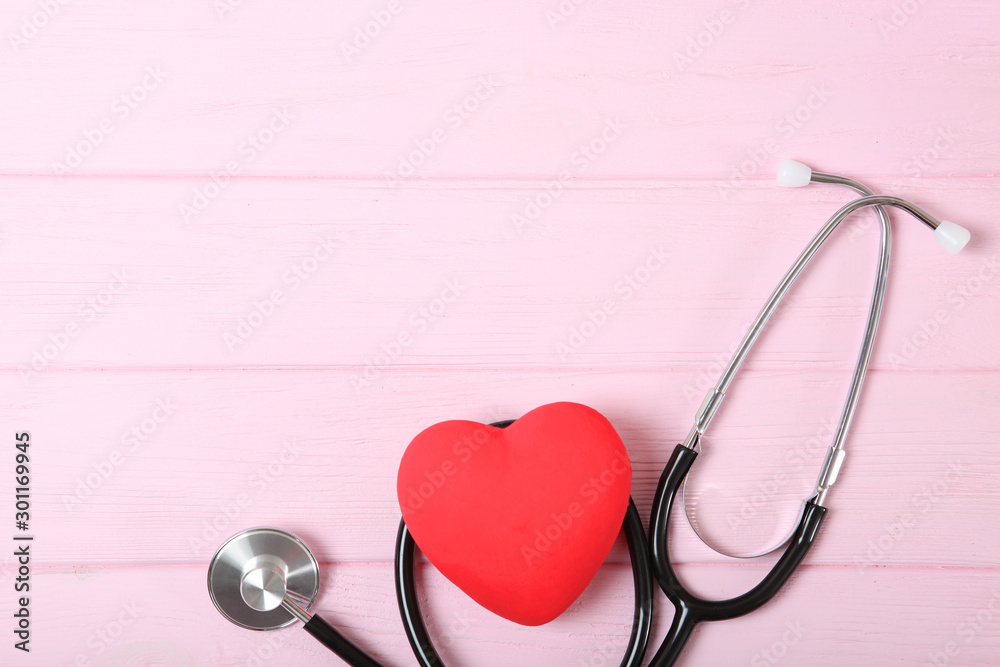 Fototapeta premium Stethoscope and heart on wooden color background. Health, medicine