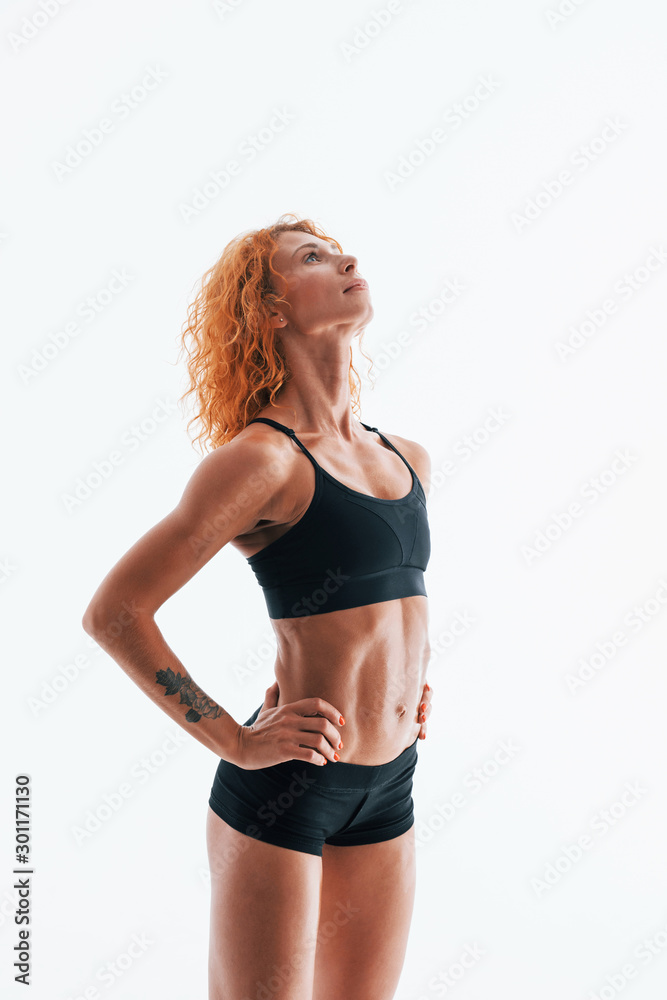 Redhead female bodybuilder is in the studio on white background Redhead female bodybuilder is in the studio on white background