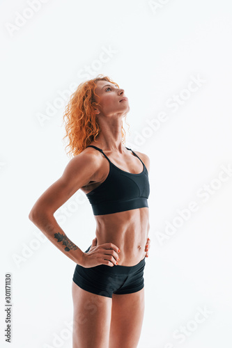 Redhead female bodybuilder is in the studio on white background