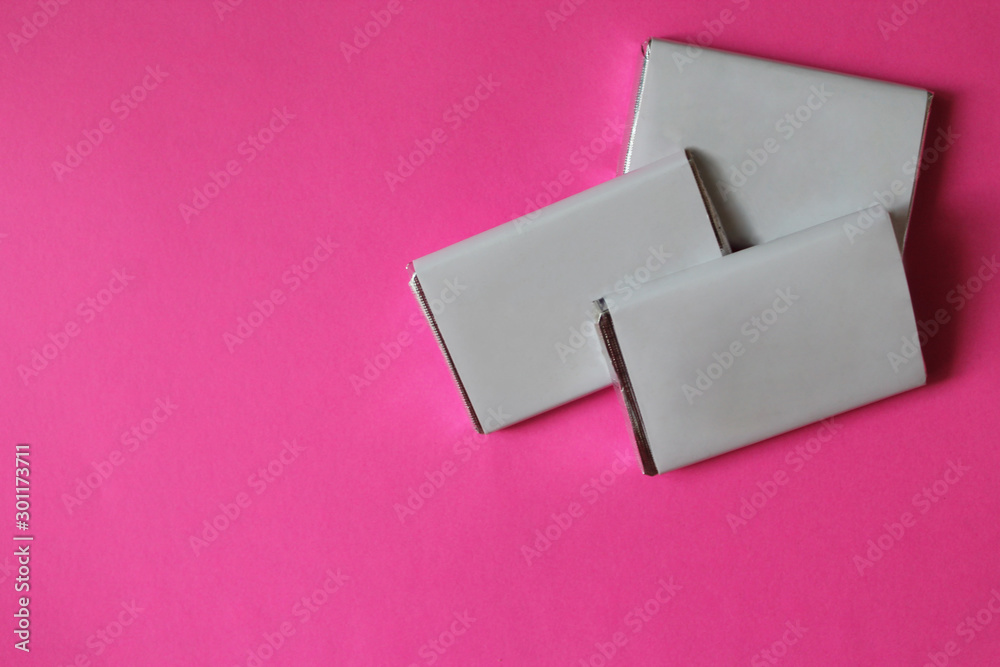 Chocolates wrapped in silver foil and white blank paper. Copy space for text. Template for greeting card, poster or invitation. Sweet candies scattered on pink smooth table. Backdrop or background Chocolates wrapped in silver foil and white blank paper. Copy space for text. Template for greeting card, poster or invitation. Sweet candies scattered on pink smooth table. Backdrop or background