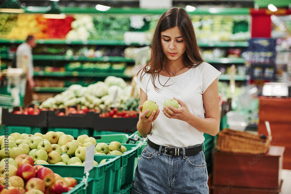 Vegetables and fruits. Female shopper in casual clothes in market looking for products