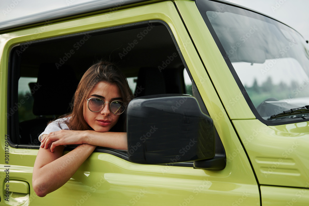 Pretty woman in the green modern car posing for the camera Pretty woman in the green modern car posing for the camera
