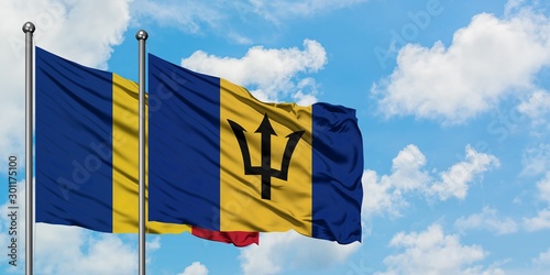 Romania and Barbados flag waving in the wind against white cloudy blue sky together. Diplomacy concept, international relations.