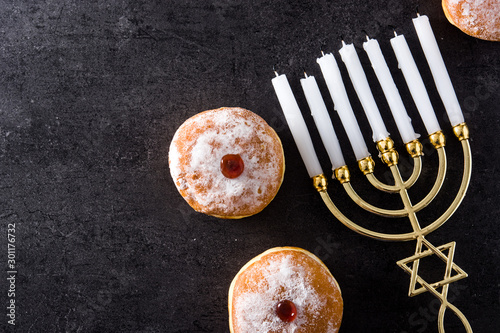 Photo Jewish Hanukkah menorah and sufganiyot donuts on black background