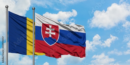 Canvas Print Romania and Slovakia flag waving in the wind against white cloudy blue sky together