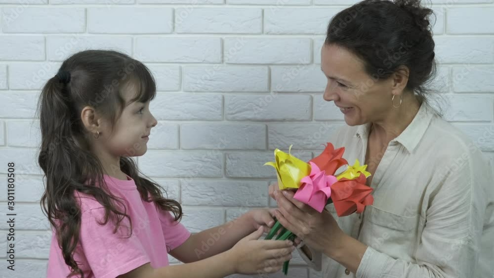 Flowers for mom. Mothers Day. A cute girl gives her mother paper flowers. Flowers for mom. Mothers Day. A cute girl gives her mother paper flowers.