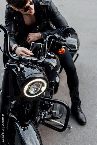 high angle view of man sitting on black motorcycle in stylish leather jacket