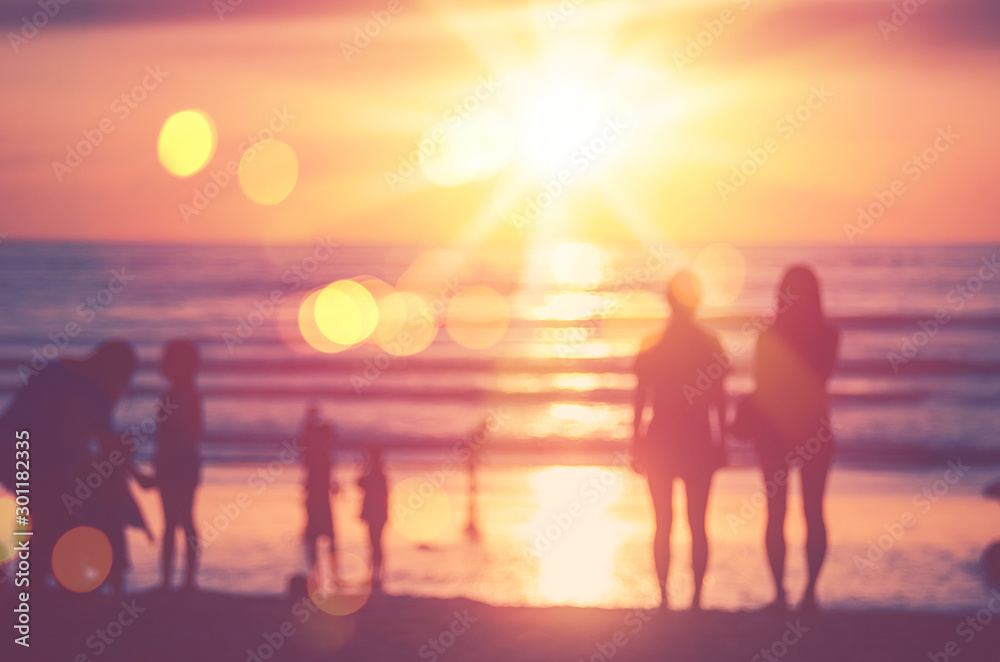 Blur people relax on tropical sunset beach with bokeh sun light wave abstract background.
