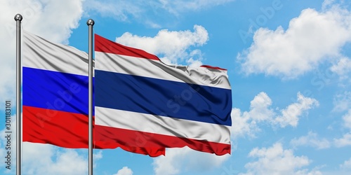 Russia and Thailand flag waving in the wind against white cloudy blue sky together. Diplomacy concept, international relations.