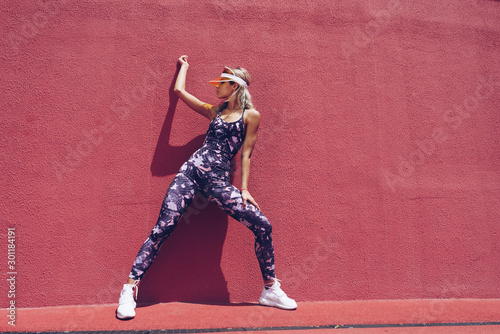 sports girl on a background of a pink wall in the park doing exercises