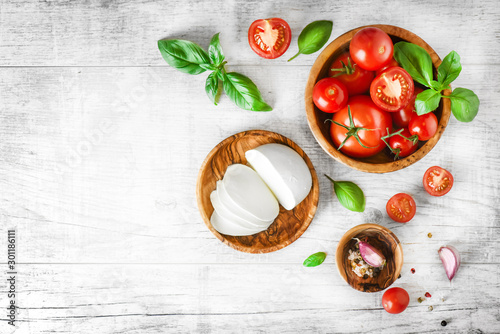 Photography Fresh finest tomatoes on white rustic board with basil and mozzarella cheese top view