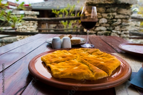 Glass of wine and hot placinta on a wooden table. photo