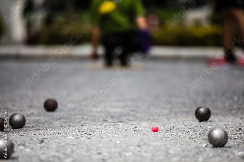 Petanque ball boules and small red jack on petanque field, Man playing petanque photo