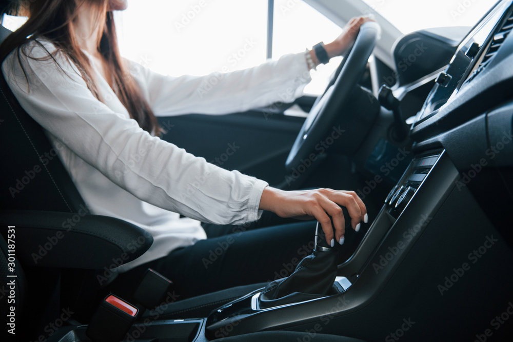 Hand on gear stick. Particle view of woman that trying modern new car in the showroom Hand on gear stick. Particle view of woman that trying modern new car in the showroom
