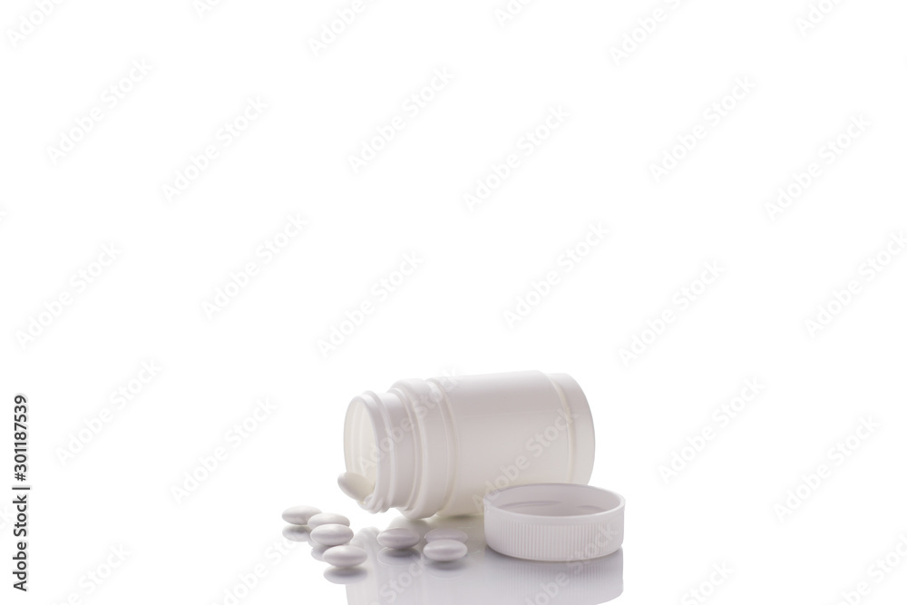 A jar with poured tablets and an open lid lies on a mirror surface on a white background in the middle. A jar with poured tablets and an open lid lies on a mirror surface on a white background in the middle.