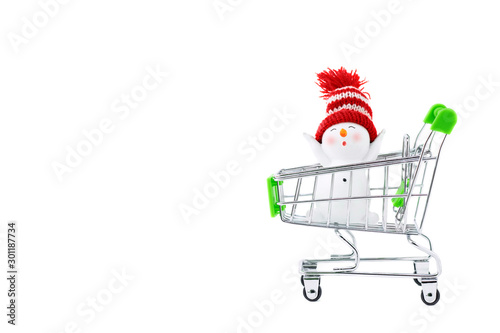 A trolley with a with happy joyful Christmas snowman. Isolated objects: toy snowman in a shopping cart, on white background, seasonal shopping concept, of Christmas and New Year shopping. Copy space © Syrtseva Tatiana