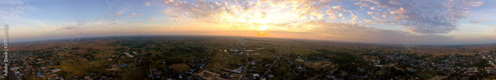 Panorama Top view Aerial photo from flying drone over village in Thailand.Cumulus sunset clouds with sun setting down on dark background.