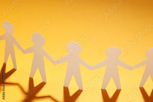 Paper cut Style concept of a leader and relationship with friendship and hand-holding of people in symbolic form on Inspiration style and modern orange paste background - 3D rendering