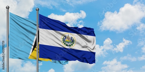 Saint Lucia and El Salvador flag waving in the wind against white cloudy blue sky together. Diplomacy concept, international relations.