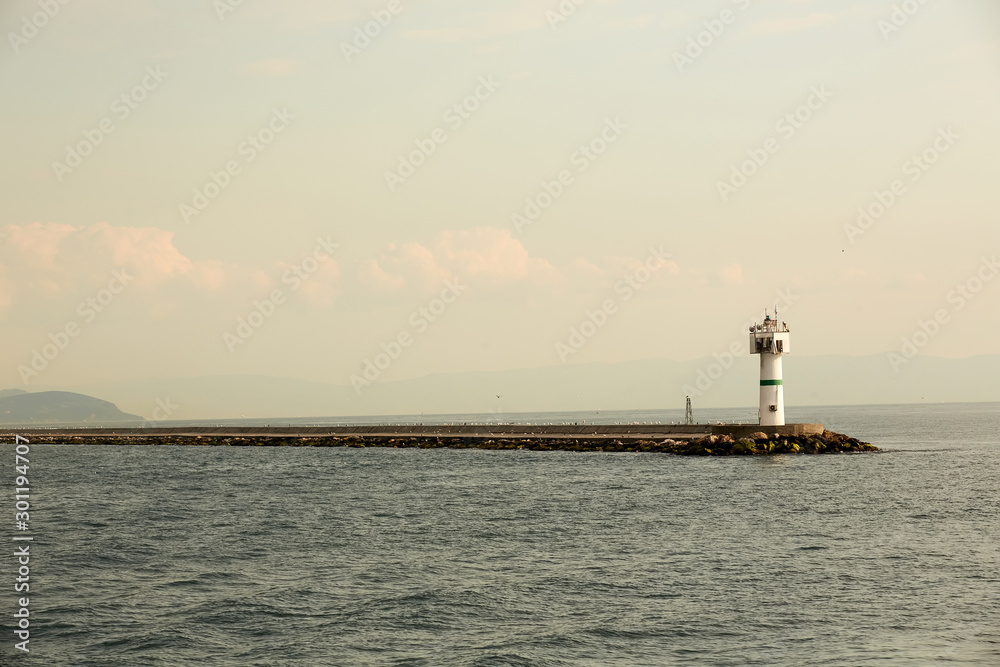 Beautiful seascape with lighthouse. Calm sea and a lighthouse on the pier. Small beacon in the endless sea. Landscape and beacon. Lighthouse