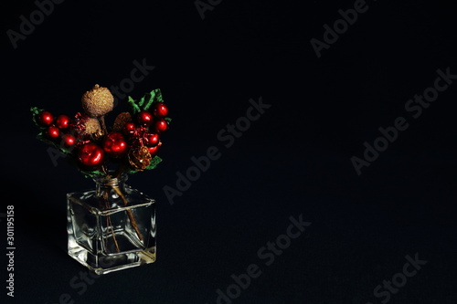 Decorative original bright Christmas bouquet in glass vase on black background. Concept Christmas, holiday, New Year, congratulatory background. Minimal style.