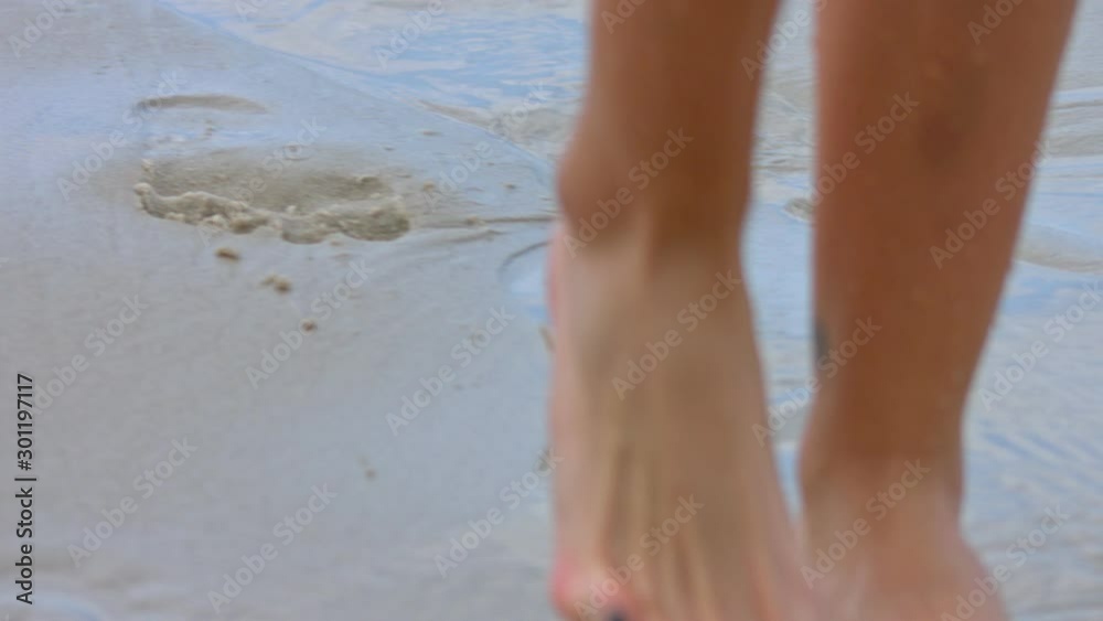 Woman feet with purple toenails on natural beach sand, slow motion
Woman feet with purple toenails on natural beach sand, slow motion