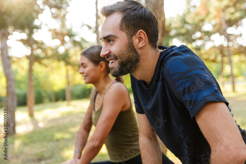 Photo of nice smiling couple doing exercises while working out