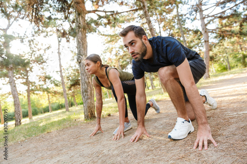 Photo of athletic serious couple doing exercises while working out