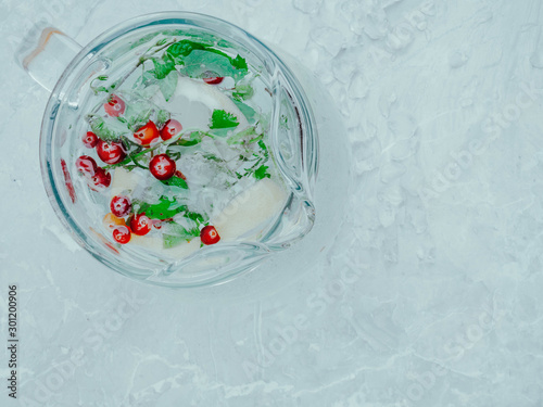 Lemonade juice with lime, lemon, mint leaves, cranberries. Fresh summer ice drink, detox water, ice cubes and glass pitcher © artemidovna