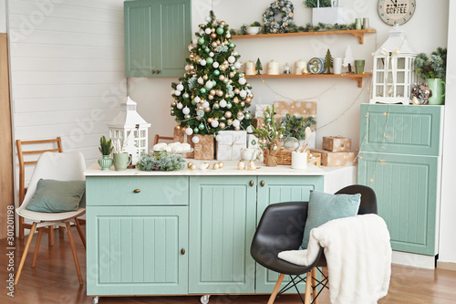 Interior light kitchen with christmas decor and tree. Turquoise-colored kitchen in classic style. Christmas in the kitchen. Bright kitchen in mint and white shades with Christmas. 