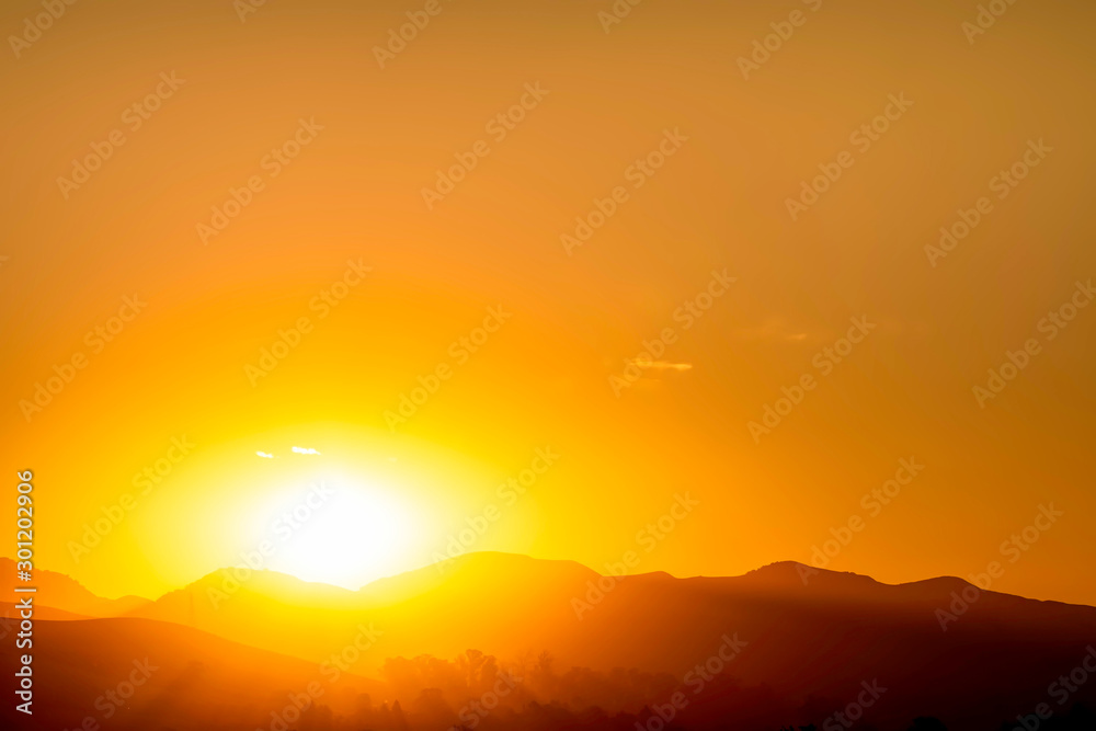 Sunset in the Silhouetted Mountains above Horizon 