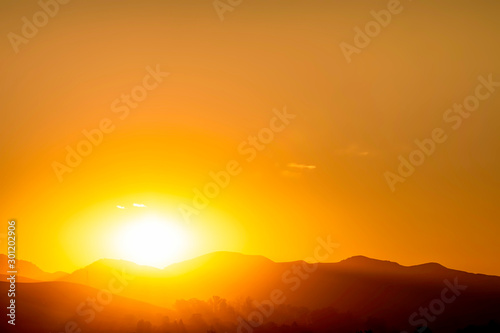 Sunset in the Silhouetted Mountains above Horizon 