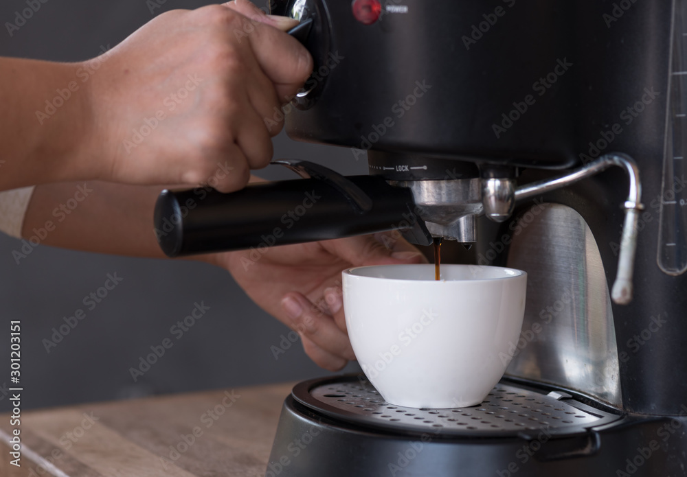 Woman hand making coffee with coffee machine on wooden counter.White cup for fresh hot coffee in the morning time at home. Woman hand making coffee with coffee machine on wooden counter.White cup for fresh hot coffee in the morning time at home.