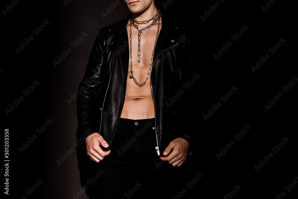 cropped view of sexy man in leather jacket with chains on neck and standing on black cropped view of sexy man in leather jacket with chains on neck and standing on black