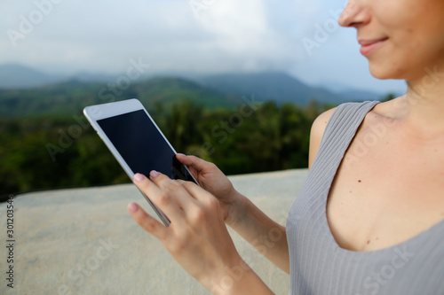 Young caucasian female person using tablet in ountains background. photo