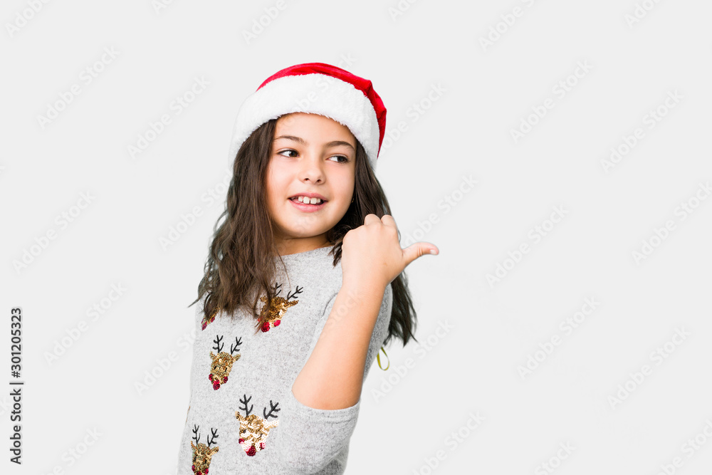 Little girl celebrating christmas day points with thumb finger away, laughing and carefree. Little girl celebrating christmas day points with thumb finger away, laughing and carefree.