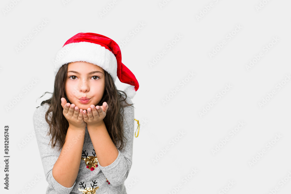 Little girl celebrating christmas day folding lips and holding palms to send air kiss. Little girl celebrating christmas day folding lips and holding palms to send air kiss.
