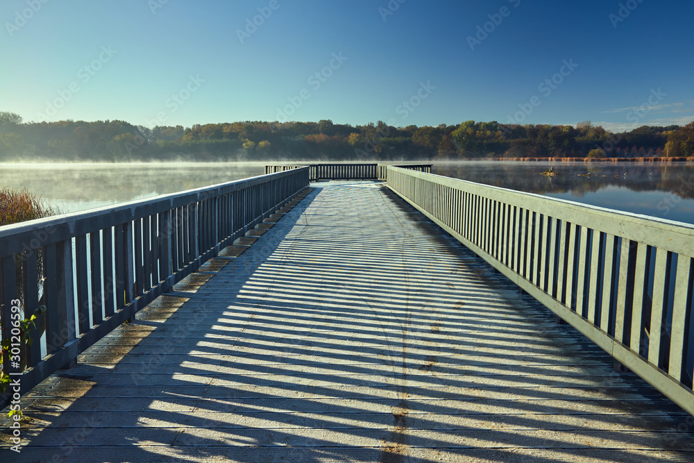 frosted wooden bridge and fog on the lake early in the morning in Poland.