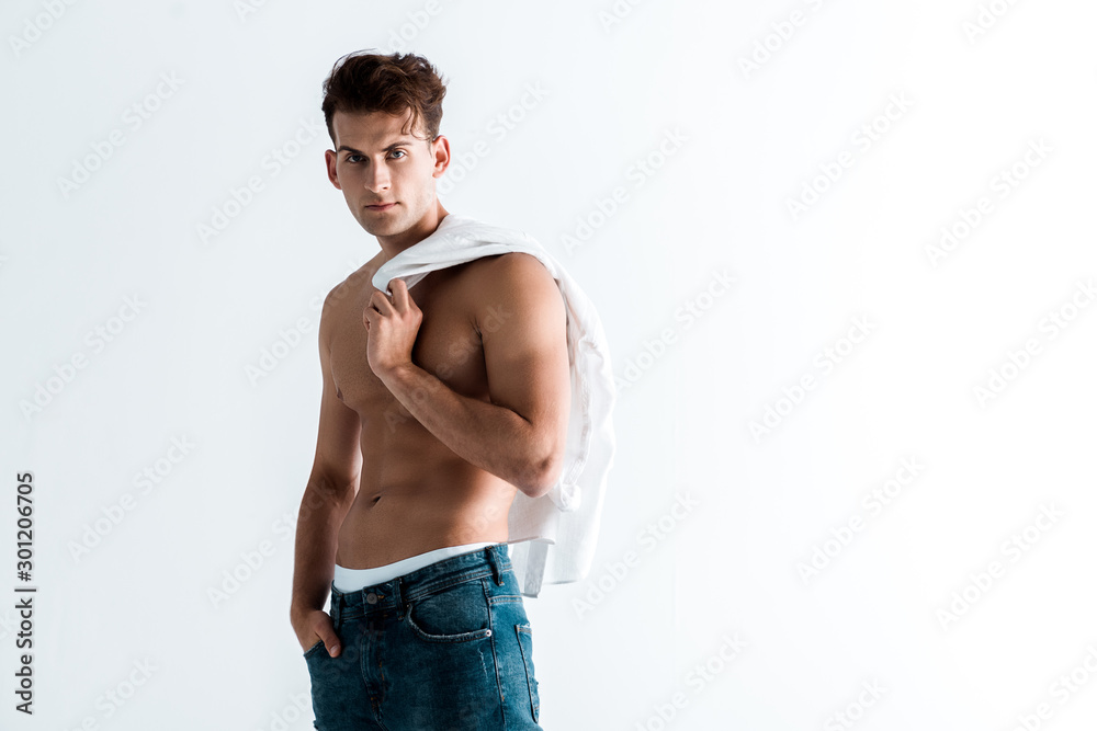 sexy man in blue jeans holding shirt and standing with hand in pocket isolated on white sexy man in blue jeans holding shirt and standing with hand in pocket isolated on white