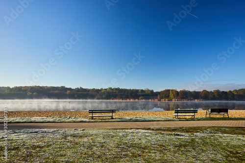 frosted wooden benches and fog on the lake in the early morning in Poland.