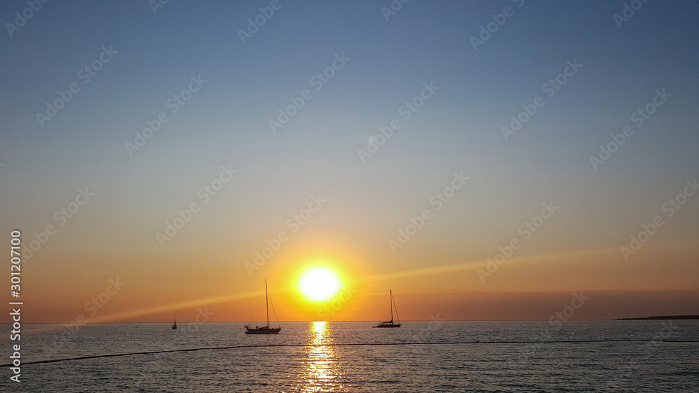Three boats and a beautiful sunset. Sailboat sails at sunset. Sailboat on the sea and beautiful sunset. Silhouette of a sailboat. Sailing boat in the sea during sunset.