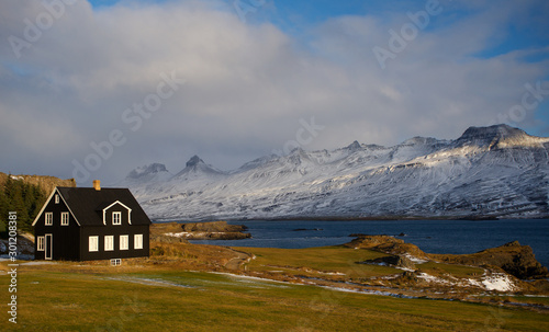Платно Traditional black house in Iceland by the fjord on the coast in winter