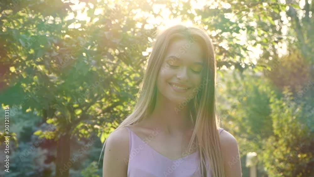 Beautiful young woman in park on sunny day. Slow motion effect