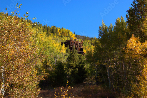 Skeleton of an old mine surrounded by fall colored aspens in the Rocky Mountains