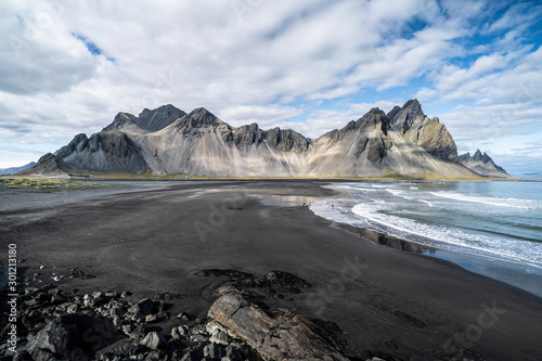 vestrahorn in southern Iceland, mirroring in calm water over black volcanic beach, landscape  photo