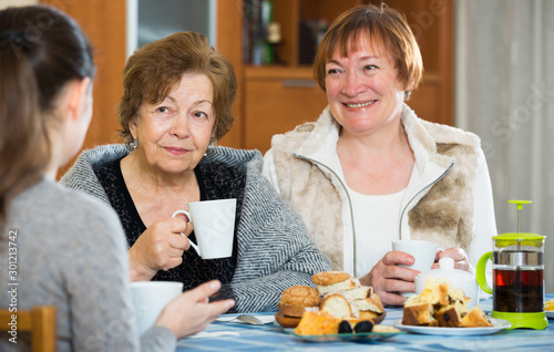 Senior women talking with girl while tea drinking