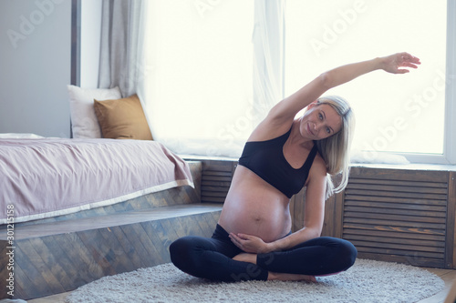 Pregnant woman doing yoga in her bedroom