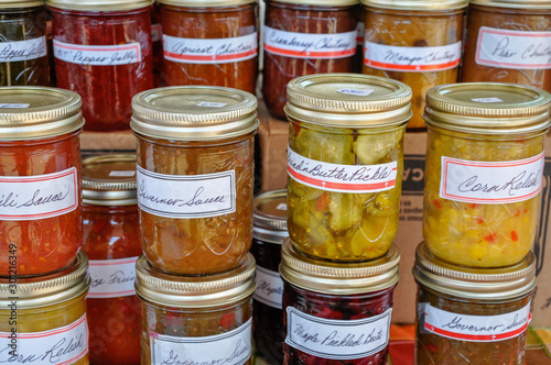 Macro of jars of homemade pickles, jams and preserves are neatly displayed and await buyers at a farmer's market. photo