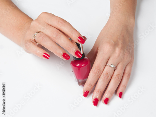Woman s hands with red manicure and a bottle of nail polish