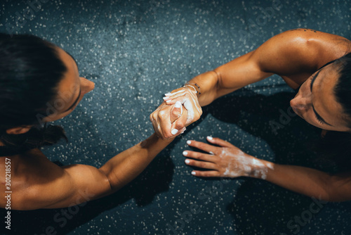 Female twins in good shape doing arm wrestling challenge in a gym photo